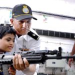 Navy personnel explains functioning of an INSAS rifle to a special child on board INS Sunayna in the Southern Naval command as part of the Navy week celebrations in Kochi on Wednesday.