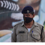 A policeman stands guard as migrants wait to board buses to reach their native places, during a government imposed nationwide lockdown as a preventive measure against the coronavirus, in Ghaziabad.
