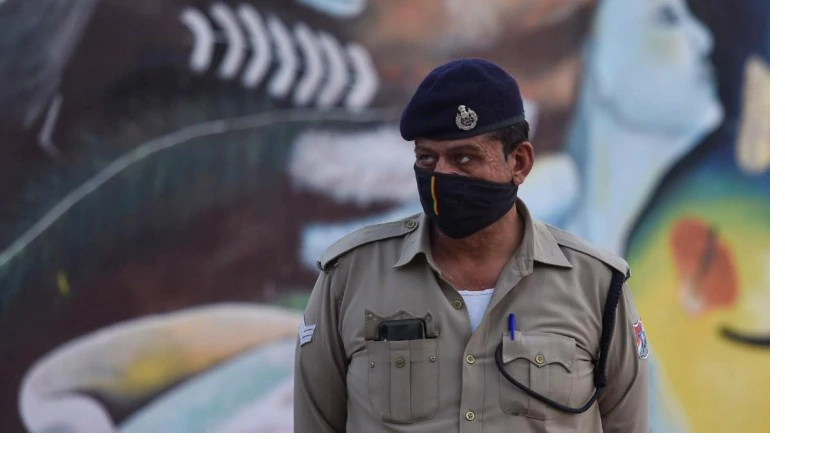 A policeman stands guard as migrants wait to board buses to reach their native places, during a government imposed nationwide lockdown as a preventive measure against the coronavirus, in Ghaziabad.