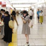 Shoppers wait outside a store as a limited number of customers are allowed into the store at a time at a shopping center in Tokyo.