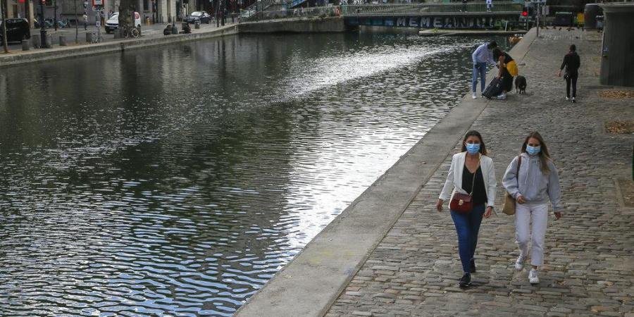 People walk along the canal Saint Martin while wearing protective face masks as a precaution against the coronavirus in Paris.