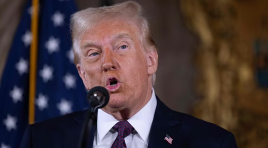 Donald Trump speaking at a podium in Mar-a-Lago during a press conference on the Middle East crisis.